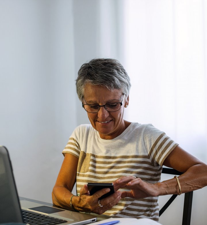 Older Woman at laptop and using mobile phone