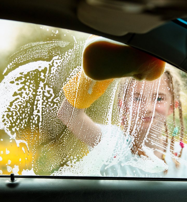 Child cleaning car with sponge