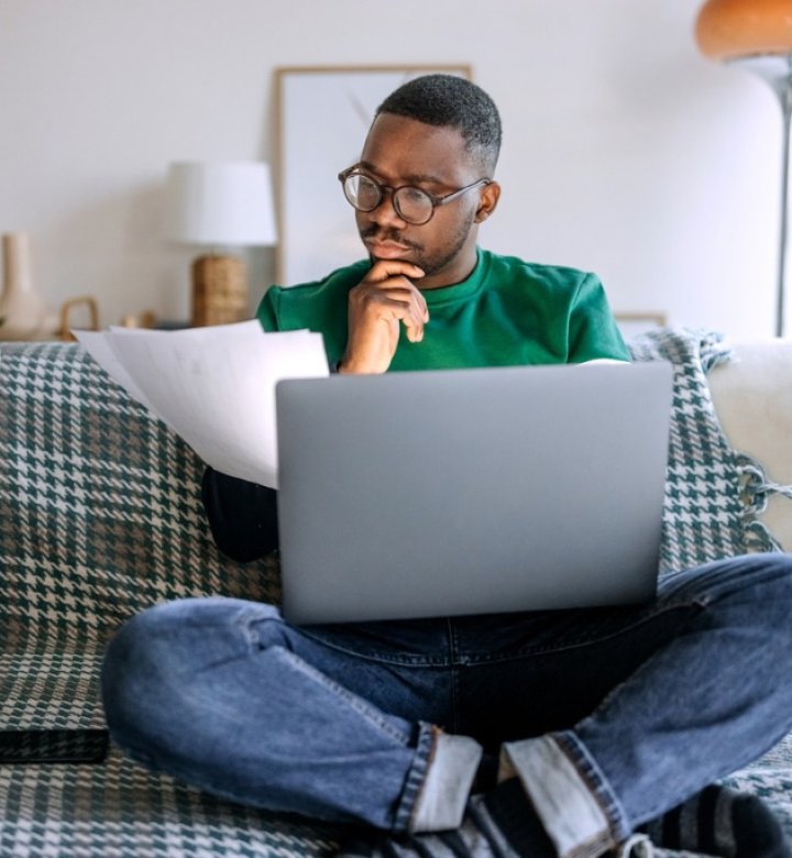 A man sits on a couch with a laptop computer.