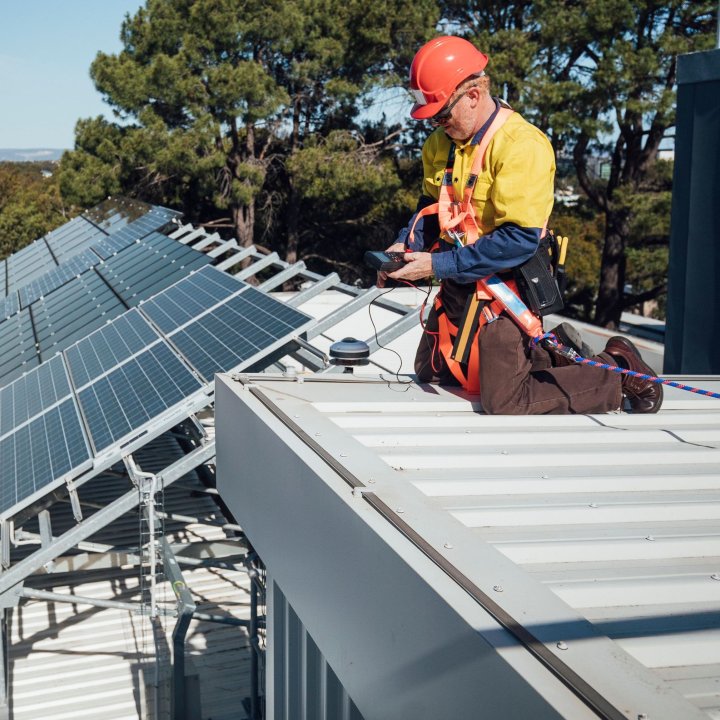 worker wearing PPE on a roof near solar panels