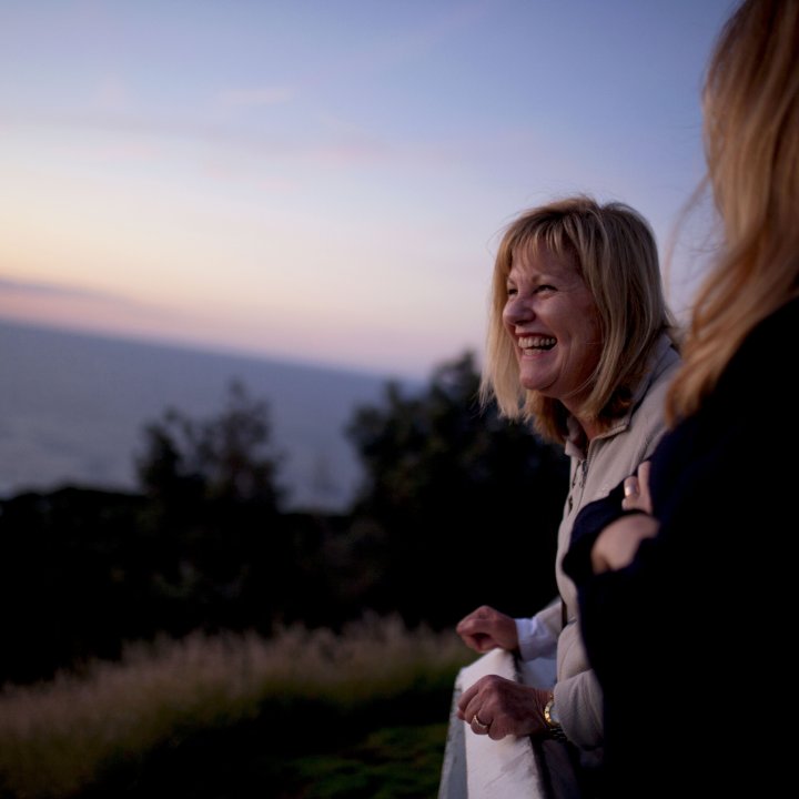 Woman laughing outside on balconey looking at sunset