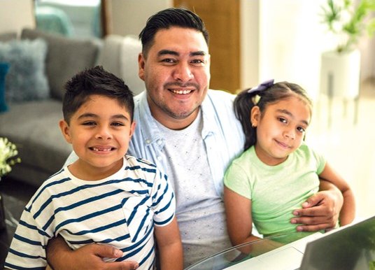 Father with his two children sitting in front of a laptop