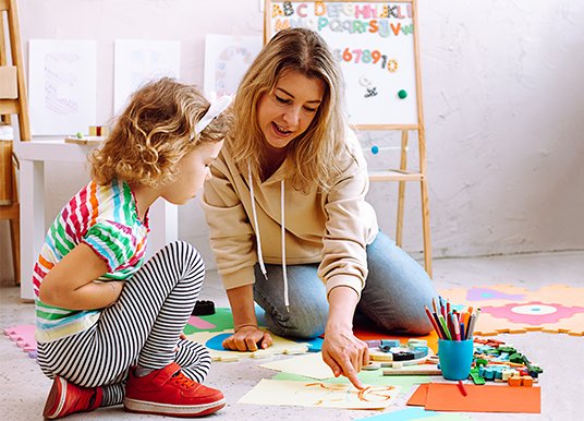 A woman with a small female child doing arts and crafts