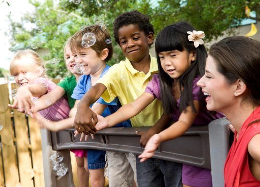 Childcare worker with kids playing with bubbles