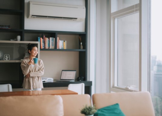 A woman standing under aircon unit in apartment