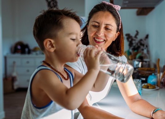 Mother and toddler fill a glass with water from the tap
